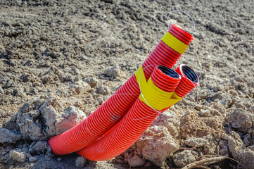 Orange-colored flexible pipes out of the ground from close