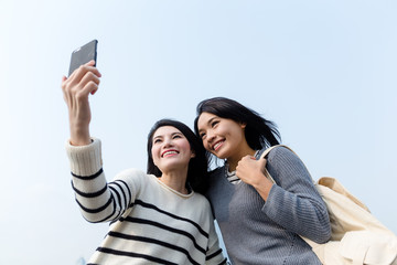 Two girls using mobile phone to take photo