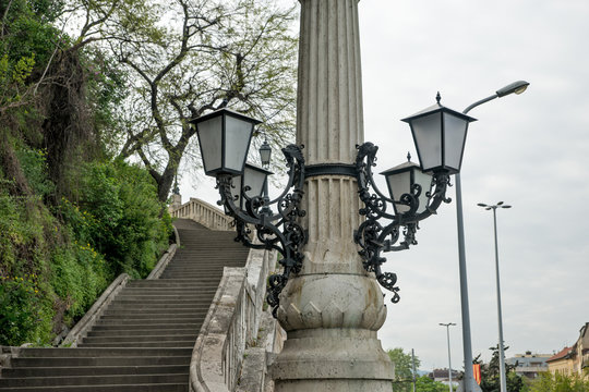 Concrete pole with street lamp next to the stairs with a stone f