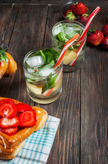 Refreshing summer drink with mint inglasses and strawberry on the vintage wooden table