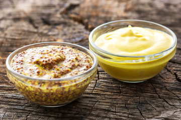Dijon mustard and mustard on wooden background