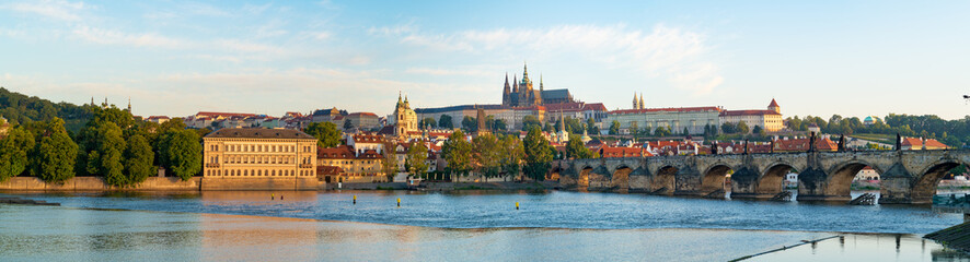 Panorama of Prague with Vltava river in the foreground, Charles Bridge on right and St.   Vitus Cathedral on the horizon. City Panorama at sunrise on a summer day
