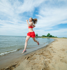 Young lady running. Woman runner running at the sunny summer sand beach. Workout near ocean sea coast. Beautiful fit girl. Fitness model caucasian ethnicity outdoors. Weight loss exercise. Jogging.