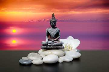 Zen or Feng-Shui background-Buddha,zen stone,white orchid flowers.In the background sunrise over the sea