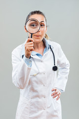 Portrait of beautiful female doctor looking through loupe.