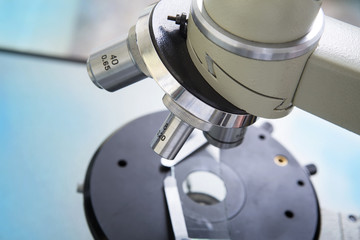 Professional microscope close-up with chemist scientific researcher hands using microscope in the laboratory interior.