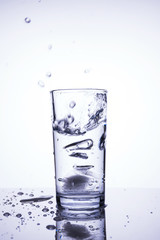 Cubes of natural ice splashing into glass with clean water