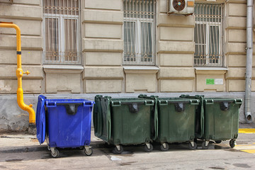 four blue and green color plastic dumpsters on the city street n