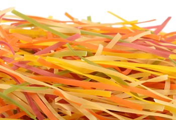 Colored uncooked Italian pasta tagliatelle on a white