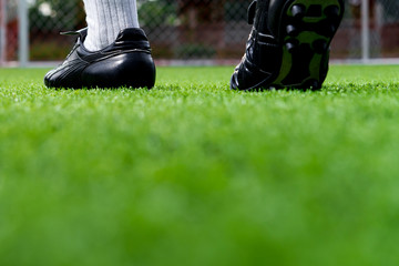Foot of soccer player or football player walk on green grass ready to play soccer match for the winner with soccer stadium backgrounds.