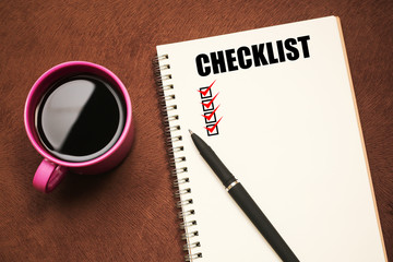 Checklist - text on notebook with a pen and cup of coffee