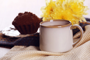 Cup of tea with autumn decor on wooden table.