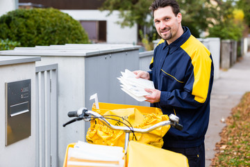 Postman delivering letters to mailbox of recipient - obrazy, fototapety, plakaty