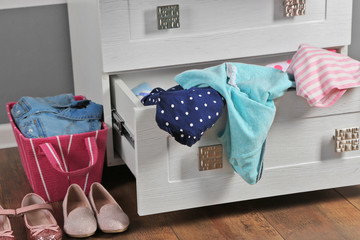 Child clothes in wooden chest of drawer, close up