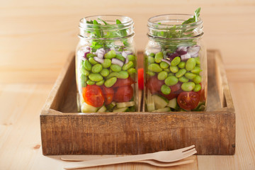 healthy vegetable salad in mason jar: tomato, cucumber, soybean,