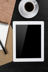 Digital tablet with cup of coffee and notebook on wooden table, closeup