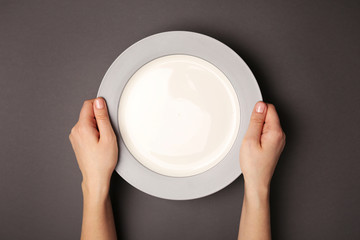 Female hands and empty plate on dark background