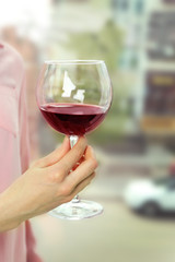 Woman holding glass of wine on blurred background