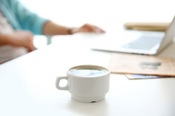 White cup of coffee and man working on background