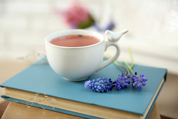 Cup of tea with flowers and old books, close up