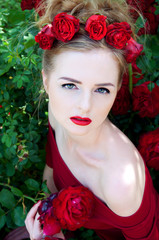 Lady vamp in crimson red dress with naked shoulders and red rose