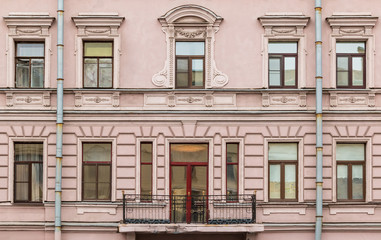 Several windows in a row and balcony on facade of urban apartment building front view, St. Petersburg, Russia.