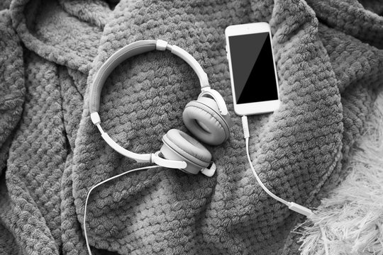 New headphones and smartphone on the blanket