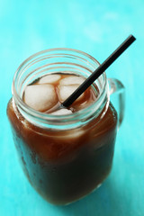 Glass jar of iced coffee on blue background