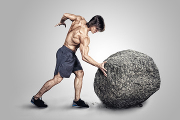 Muscular male pushing big stone.