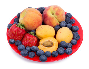 Naklejka na ściany i meble Fresh blueberry, strawberry, peach and apricot on a red plate
