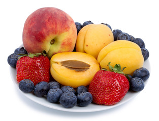 Naklejka na ściany i meble Fresh blueberry, strawberry, peach and apricot on a white plate