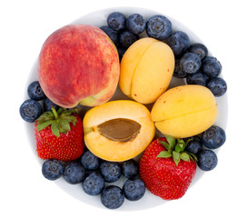 Fresh blueberry, strawberry, peach and apricot on a white plate