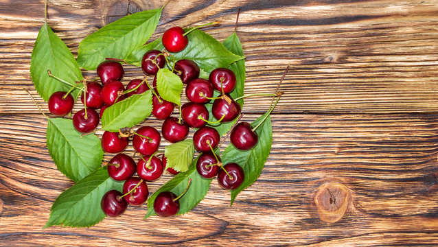 Cherries with leaves on the wooden background