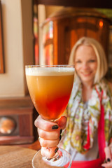 Beautiful girl drinking beer from the glass cup.