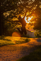 Girl jumps in the sunset till walking on the road.