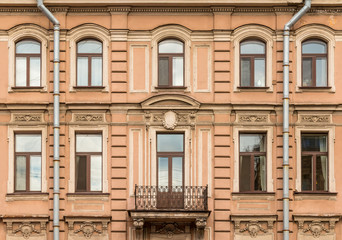 Several windows in a row nd balcony on facade of urban apartment building front view, St. Petersburg, Russia.