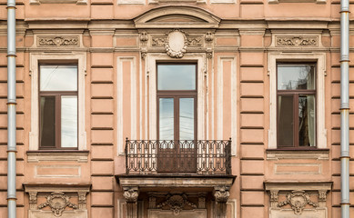 Three windows in a row nd balcony on facade of urban apartment building front view, St. Petersburg, Russia.