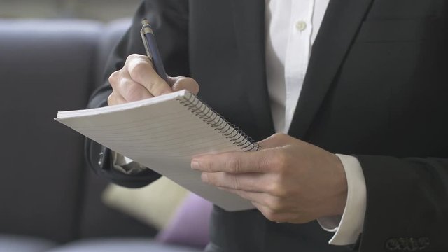 Businessman taking notes on spiral bound paper pad