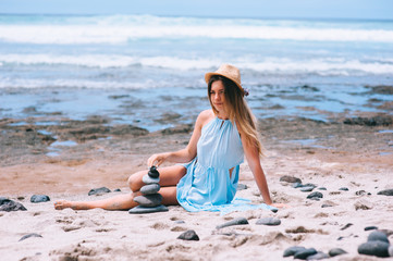 Fototapeta na wymiar Stack of pebble stones at the beach with a beautiful woman behin
