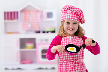 Little girl playing with toy kitchen