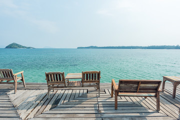 Fototapeta na wymiar Wooden chair on wooden floor with beautiful ocean and blue sky scenery