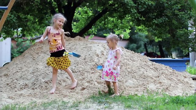 Two little girls dancing in front of the camera depicting guitar playing in the sand