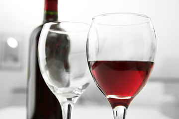 Glass of red wine with bottle on blurred interior background