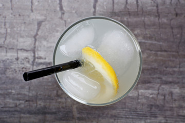 Glass of lemon soda with ice on rustic wooden background