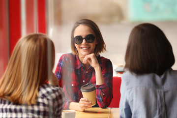 Young happy women drinking coffee and talking in cafe