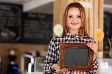 Fototapeta na wymiar Young woman in cafe holding wooden board