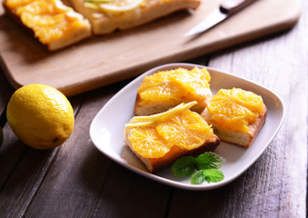 Plate with delicious citrus cake on wooden background