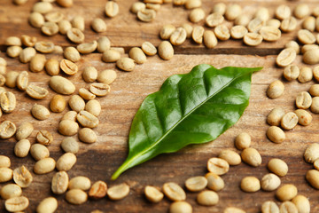 Coffee beans and green leaves on wooden background