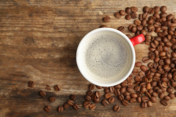 Cup of coffee with beans on wooden background