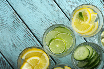 Fresh cocktails with soda, lime, lemon and cucumber on a wooden background